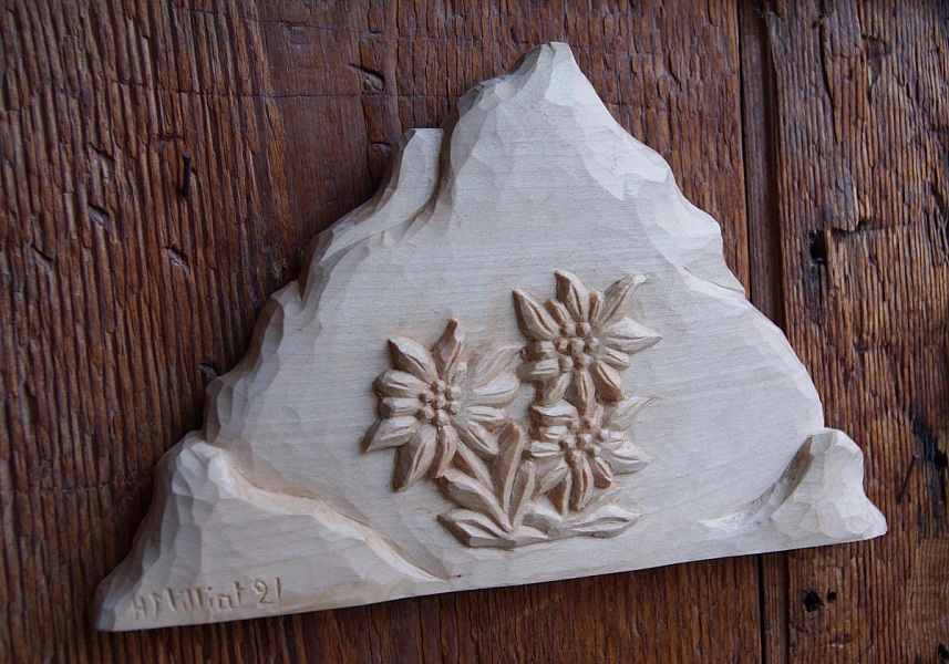 Sculpture en bois représentant une montagne et des edelweiss.
